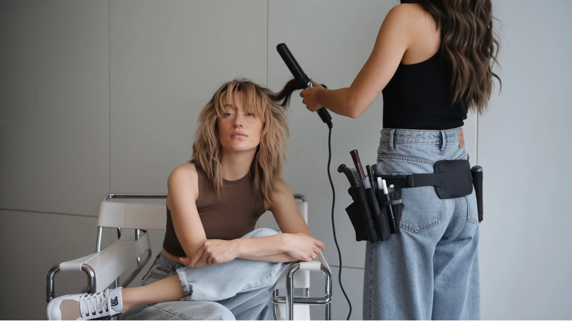 Styling-coiffure-professionnelle-formation-sorado Coiffeuse en train de styliser les cheveux d’une modèle avec un fer à boucler