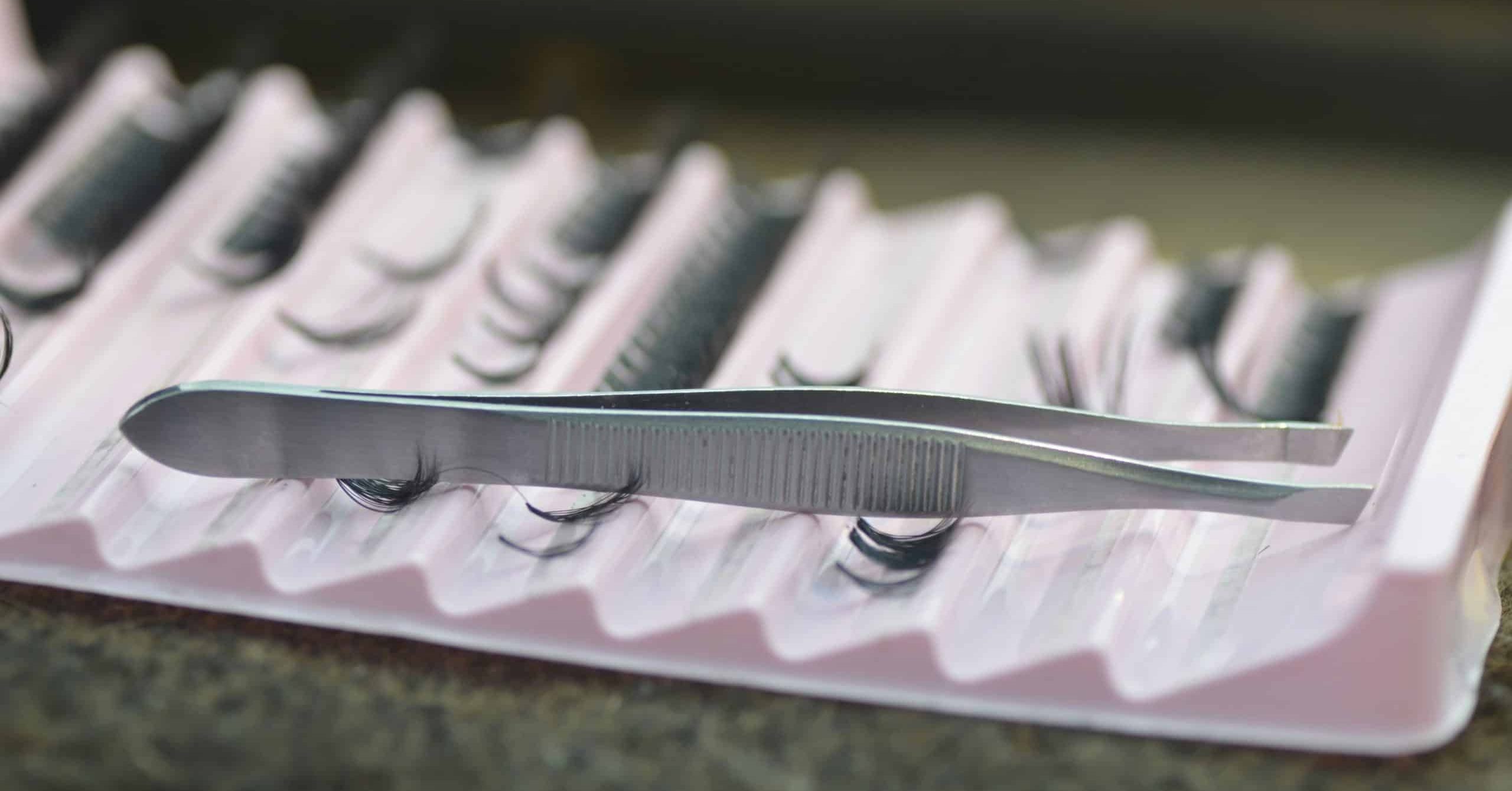 Matériel professionnel pour extensions de cils : pinces et faux cils sur plateau de travail